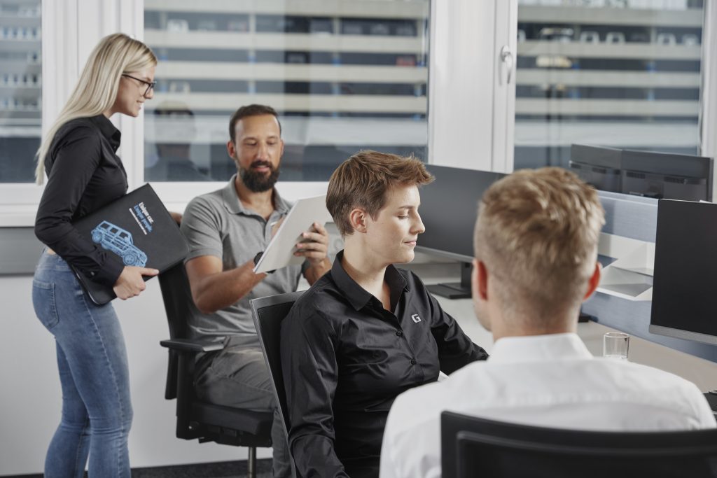 Mitarbeiter:innen der Mercedes-Benz G GmbH bei der Arbeit im modernen Büro.