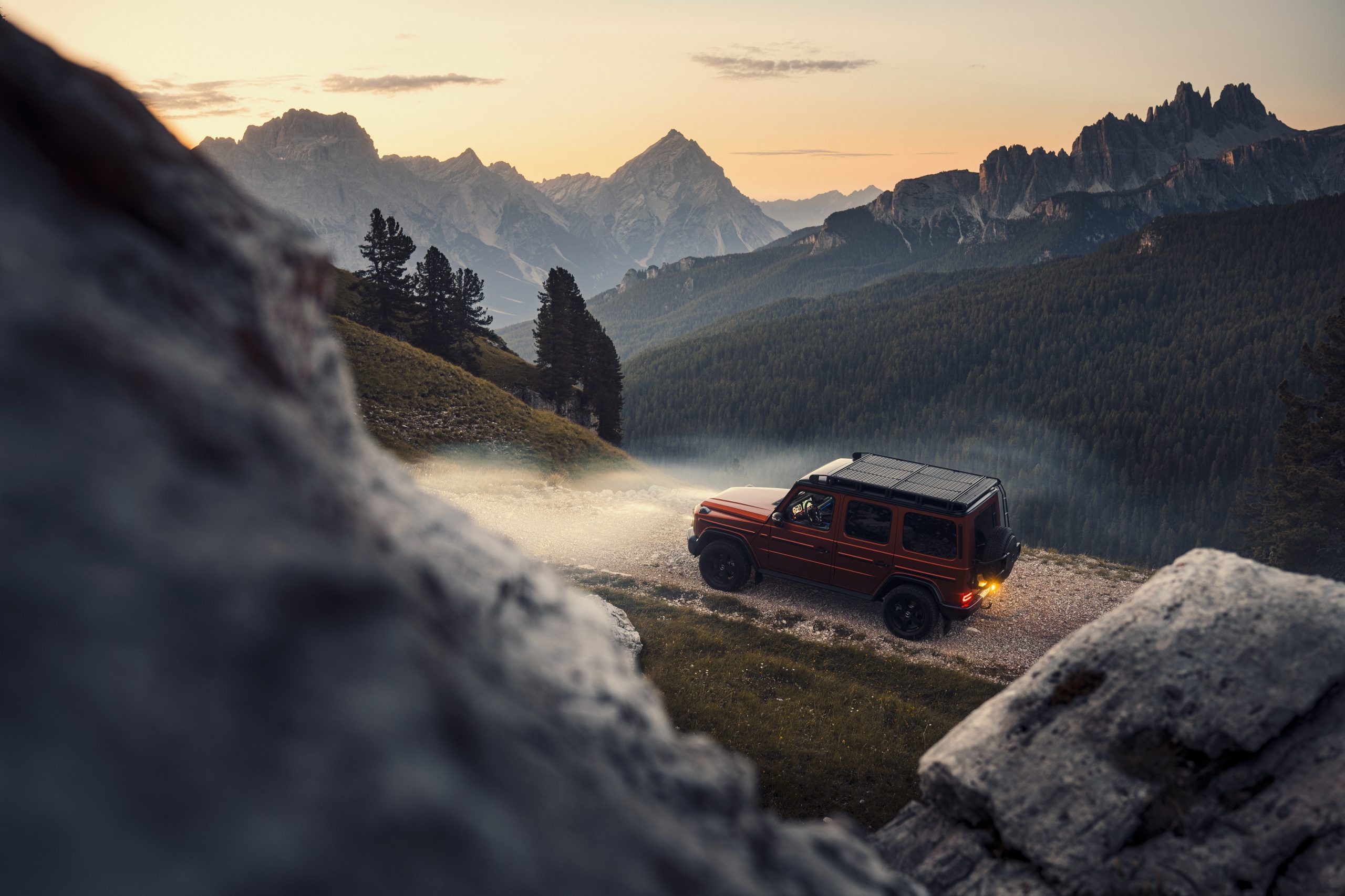 Orange Mercedes-Benz G-Klasse fährt auf einem steinigen Weg in den Bergen.