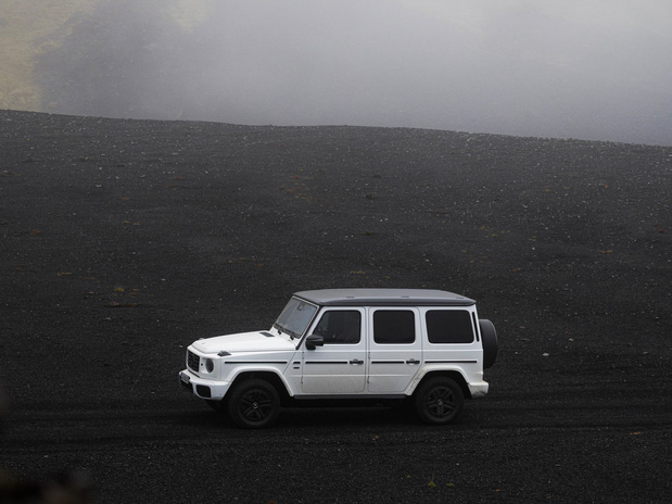 Weiße Mercedes-Benz G-Klasse auf schwarzem Sand.