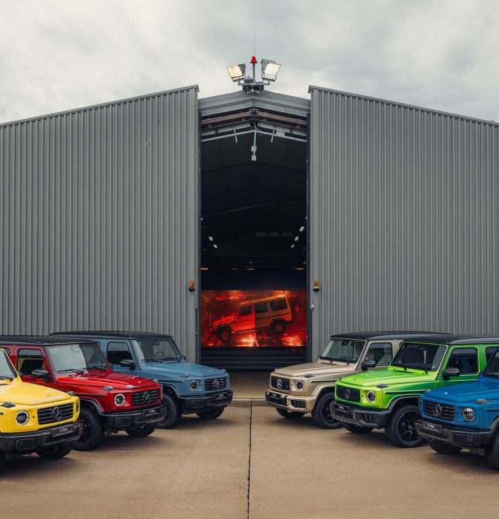 Mehrere farbige Mercedes-Benz G-Klasse Fahrzeuge vor dem G-Class Experience Center in Graz.